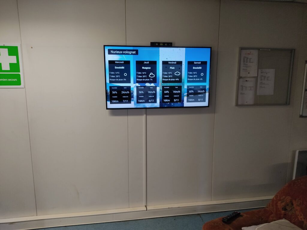 Écran mural affichant la météo locale dans une salle d’attente ou un espace d’accueil.