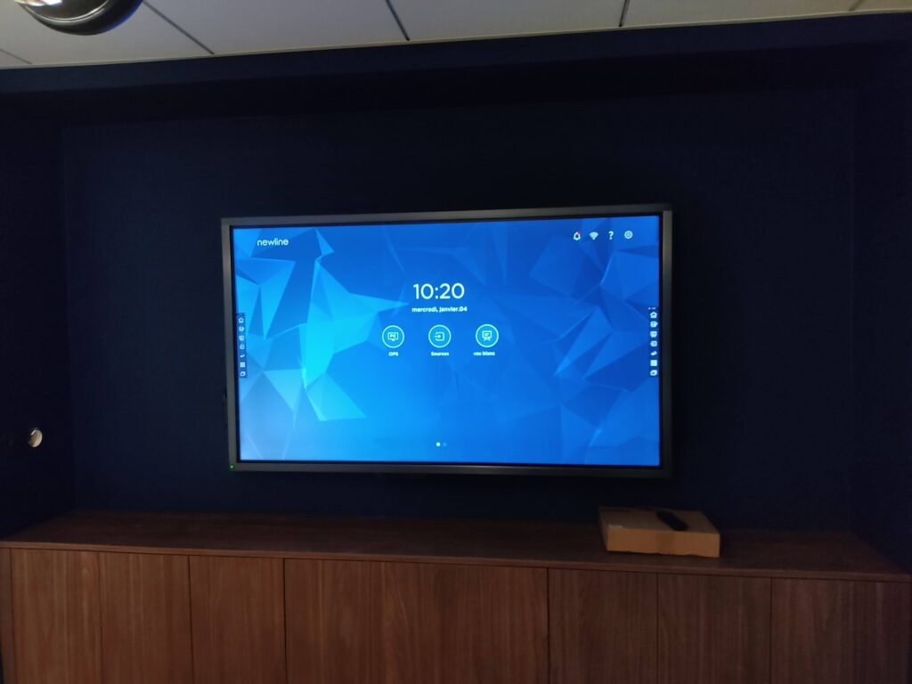 Écran interactif Newline installé en salle de réunion avec interface OPS affichée.