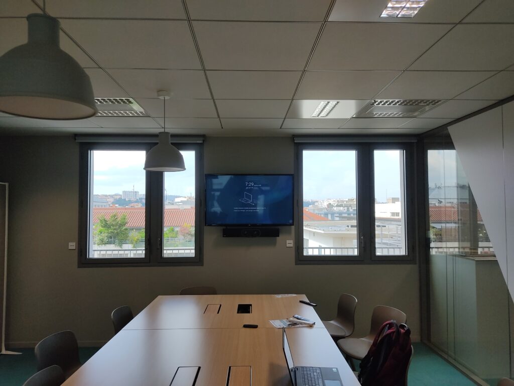 Écran de visioconférence Microsoft Teams Room installé dans une salle de réunion moderne.