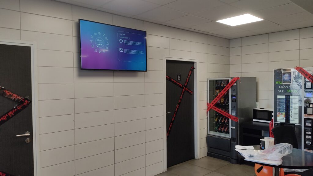 Écran mural affichant un horoscope numérique dans une salle de pause décorée.