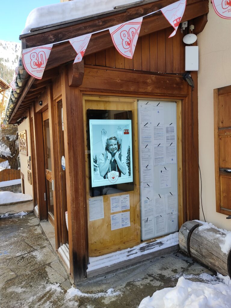 Écran d’affichage dynamique installé en vitrine de restaurant en station, contenu promotionnel visible depuis l’extérieur.