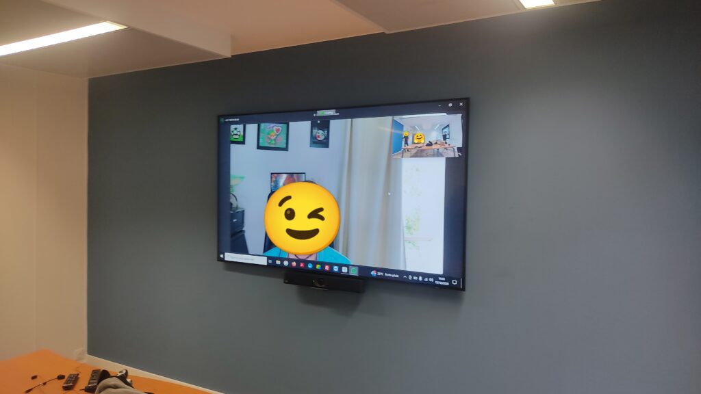 Installation d’un écran mural pour salle de réunion avec système de visioconférence Zoom en fonctionnement.