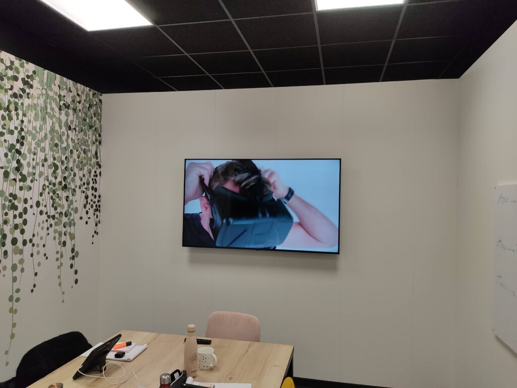 Salle de réunion équipée d’un écran professionnel affichant une démonstration VR, installation audiovisuelle complète.