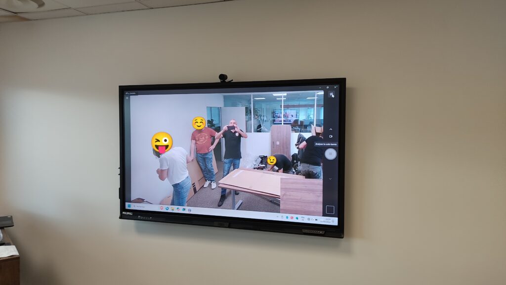 Écran mural affichant une scène de montage en entreprise, installation audiovisuelle en cours.