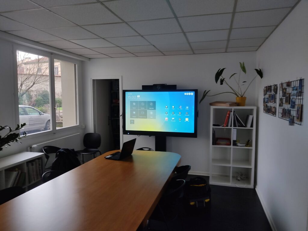 Installation complète d’un écran mural avec barre de son et caméra pour visioconférence professionnelle.